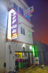 埃尔加德Amudha Hotels & Restaurant的建筑物一侧有 ⁇ 虹灯标志的商店