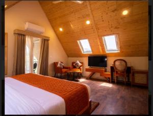 柴尔Samsara Luxury Cottages & Spa !! Best Resort in Chail的一间卧室配有一张床、一张书桌和一台电视
