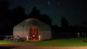 浦耳Glamping at South Lytchett Manor的帐篷,晚上在田野里摆放桌子