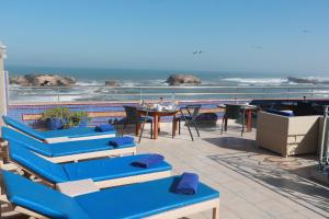 索维拉Riad Perle D'Eau的一个带蓝色椅子和桌子的庭院和大海