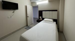 巴里沙尔Hotel Kingfisher - Barishal的一间小卧室,配有一张床和一台平面电视