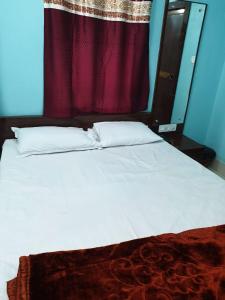 德奥加尔Hotel Ambika的卧室配有白色的床和红色窗帘