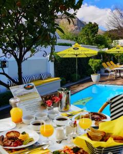 弗朗斯胡克Fleur du Soleil Luxury Guesthouse的游泳池旁的餐桌,供应食物和饮料
