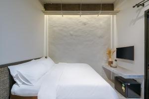 曼谷Siam Shelter Bangkok的卧室配有白色的床和电视。