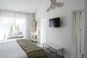 科英布拉CoimbraAmeias的白色的客房设有一张床和墙上的电视