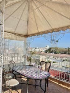 拉巴特Riad Najiba的阳台上配有桌椅和遮阳伞