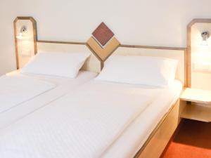 Nickenich布尔格克拉尔斯酒店的配有白色床单的客房内的两张床