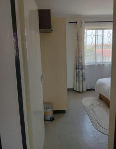 内罗毕Sandrock Residence的一间卧室设有一张床和一个窗户,地面铺有地板