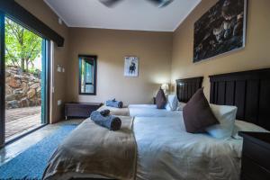 巴卢莱自然保护区Maninghi Lodge的一间卧室设有两张床和大窗户