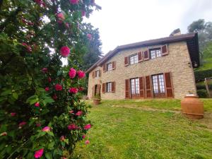 佩夏Villa Camelia Tuscany的前面有粉红色玫瑰的大砖房子