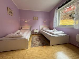 弗洛姆Svingen Guesthouse - Panoramic Fjord Views in Flåm的紫色墙壁和窗户的客房内的两张床