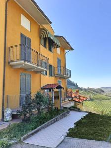 蒙福特达尔巴Soggiorno con splendida vista的黄色的建筑,旁边设有阳台