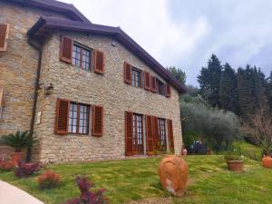 佩夏Villa Camelia Tuscany的院子里的石屋,有红色百叶窗