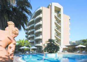 阿尔巴·阿德里亚蒂卡Residence Torre Del Mar的一座带游泳池的建筑前方的雕像