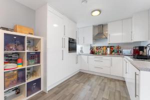 CheamTranquility的白色的厨房配有白色的橱柜和木地板。