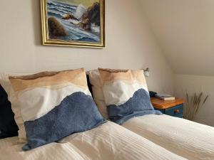 北内伯尔Nygaard B&B的一张带两个枕头的床和墙上的绘画