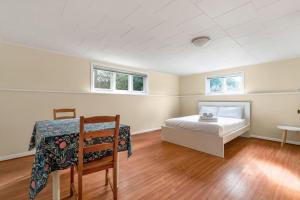 温哥华Tranquil Haven near Attractions: 4 BD Suite的一间卧室配有一张床、一张桌子和两个窗户