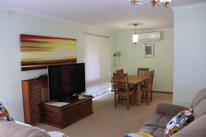 珀斯Comfort and Convenient的客厅配有平面电视和桌子。