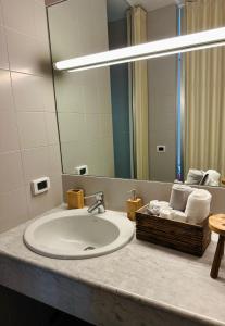 伊夫雷亚Eporedia 222的浴室水槽配有镜子和一篮毛巾