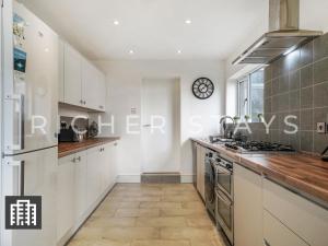 沃特福德Watford Large 5BR Home - Contractors & Families的厨房配有白色橱柜和墙上的时钟