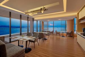 名古屋Batam Marriott Hotel Harbour Bay的一间带桌椅的海景餐厅