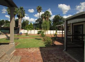 贝拉贝拉BelaBela Guesthouse的房屋的背景是带棕榈树的庭院