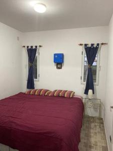 罗萨里奥Hostal del Sol - Fisherton的一间卧室配有红色的床和蓝色窗帘