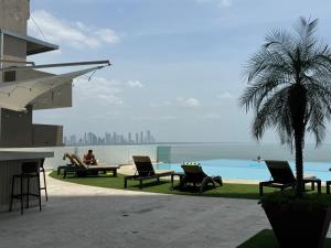 巴拿马城Apartamento en Panama y Punta Pacífica, Céntrico y Costa de Panamá的一群人坐在游泳池旁的椅子上