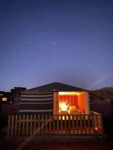 瓦迪拉姆Glamp Camp Wadi Rum的一间小房子,晚上有窗户照亮
