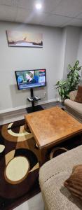 温尼伯New Stylish 2-Bedroom Basement Suite的客厅配有桌子和平面电视。