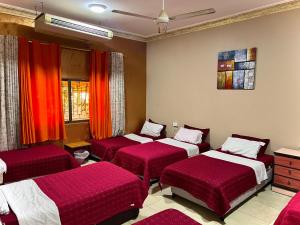亚喀巴Al-Amer Hostel 1的红色床单的客房内的三张床