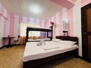 公主港Duchess Sophia's Pension的卧室配有一张床铺,位于一间拥有粉红色和紫色条纹的房间