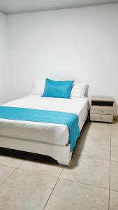 波帕扬Hotel Monarka-Edificio的一张白色的床,上面有蓝色的枕头