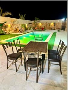 Al Ramaشاليه البحر الميت الرامة-Deadsea的游泳池前的一张桌子和椅子
