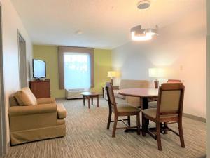 萨尔弗Holiday Inn Express & Suites Sulphur - Lake Charles, an IHG Hotel的客厅配有桌椅和电视。