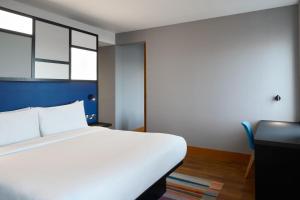伦敦雅乐轩伦敦埃克塞尔酒店的卧室配有白色的床、书桌和窗户。