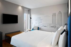 伦敦雅乐轩伦敦埃克塞尔酒店的卧室配有白色的床和平面电视。