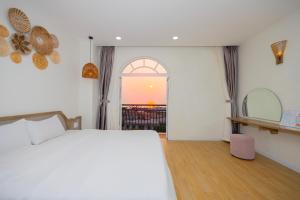 富国Lily House Hotel Phu Quoc的一间卧室设有一张床和一个享有日落美景的窗户
