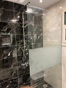 Al Ma‘şarahشقة فندقية فاخرة的带淋浴和黑色大理石墙的浴室
