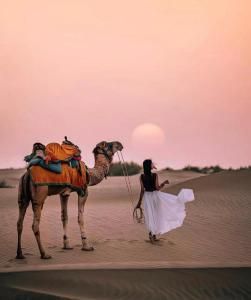 斋沙默尔Jaisalmer Sam Sand Dunes Luxury Camps的站在沙漠骆驼旁的女人