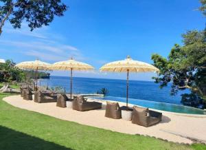 卡朗阿森Bali Cliff Glamping的游泳池旁的一排椅子和遮阳伞