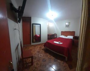 阿亚库乔HOSPEDAJE BUENA VISTA的一间卧室配有红色的床和镜子