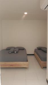 卢武克Wisma Delima的白色楼层的客房内设有两张单人床。