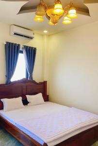 波来古市SAIGON - PLEIKU HOTEL的一间卧室配有一张带蓝色窗帘的床和一扇窗户