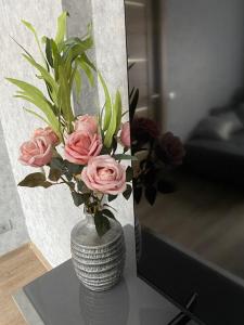 叶卡布皮尔斯Dzīvoklis centrā的一面镜子旁的桌子上镶着粉红色玫瑰的花瓶