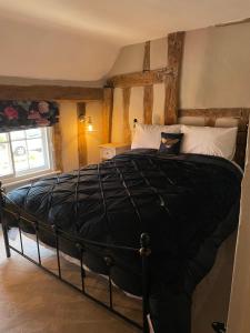 拉文纳姆Little Mouse Cottage的一间卧室,卧室内配有一张黑色大床