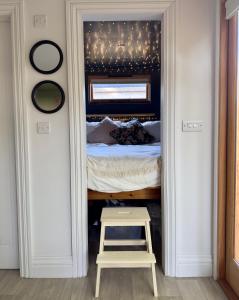布兰德福德福鲁姆The Snug: Dorset hideaway的卧室配有一张床和门廊凳子