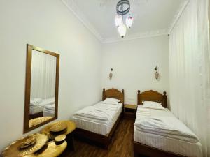 布哈拉Best Hotel Muqaddam的配有镜子和桌子的客房内的两张床