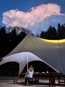 张家界Zhangjiajie National Forest Park Camping的坐在长凳上大帐篷下的女人