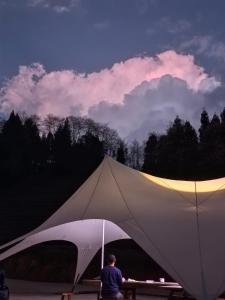 张家界Zhangjiajie National Forest Park Camping的坐在大白色帐篷内的男人